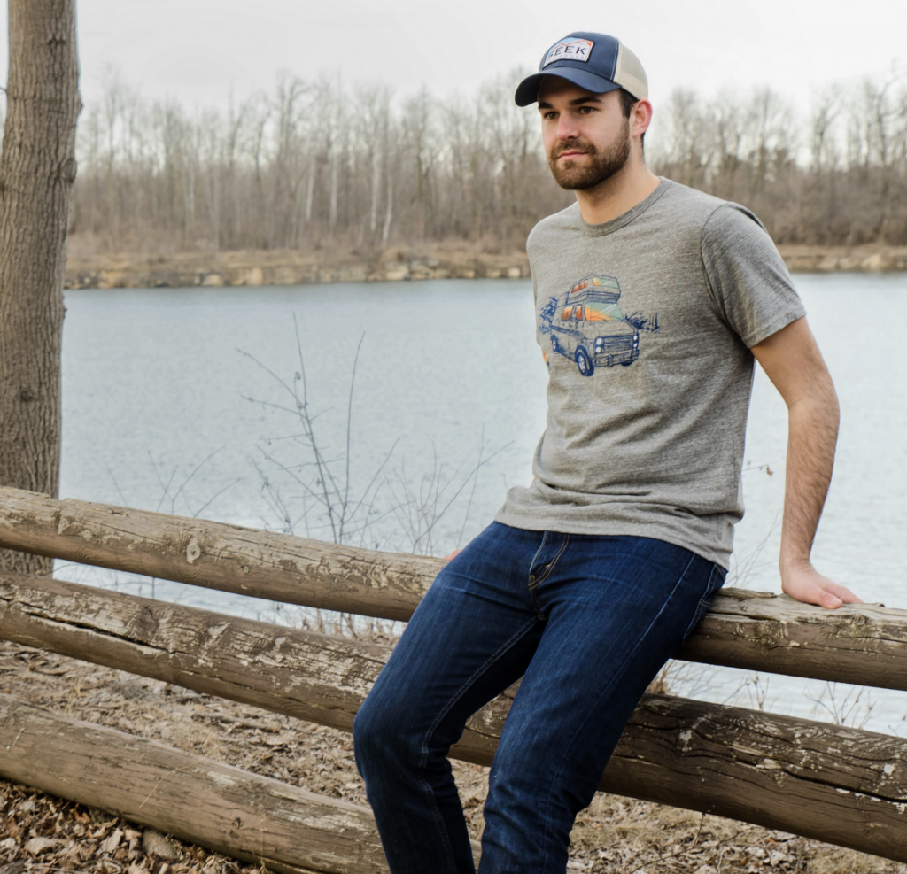 Man wearing shirt leaning on bench by lake